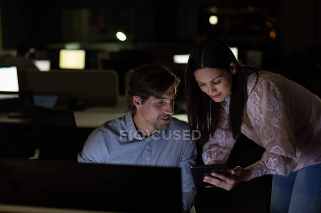 Front view of young multi-ethnic office executives discussing over digital tablet in a modern office. They are working late — Stock Photo