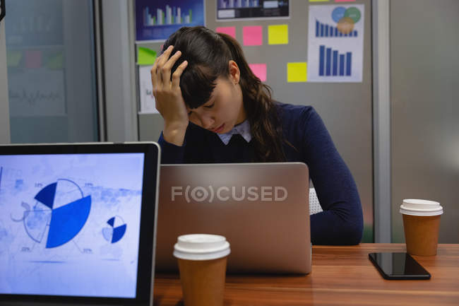 Vista frontal de empresária sentada deprimida no escritório na mesa — Fotografia de Stock