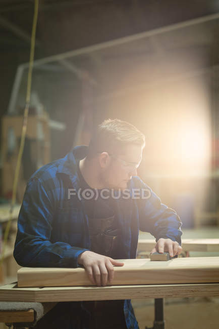 Вид сбоку плотника, измеряющего дерево в мастерской — стоковое фото