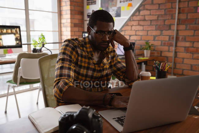 Vista anteriore di uomo d'affari premuroso che lavora sopra computer portatile in ufficio — Foto stock