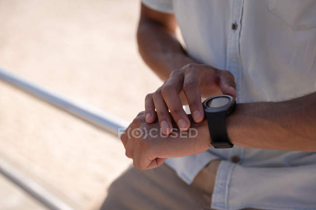 Средняя часть человека использует умные часы на пляже — стоковое фото