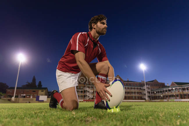 Tiefansicht eines Rugbyspielers, der nachts den Rugbyball auf dem Kickabschlag im Stadion platziert — Stockfoto