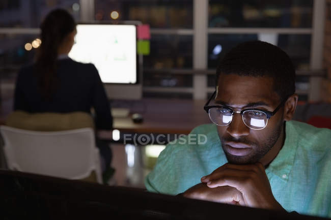 Vista frontal do empresário pensativo afro-americano que trabalha no escritório em mais de computador — Fotografia de Stock