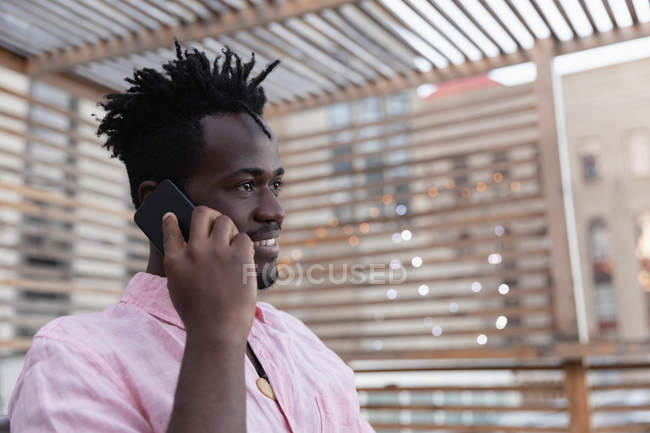 Side view of African american man talking on mobile phone in balcony at home — Stock Photo
