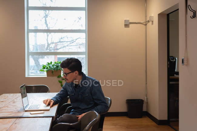 Вид збоку бізнесмена, який працює над ноутбуком на офісній конференції — стокове фото