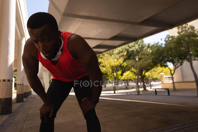 Фронтальний вид молодих афро-американських fit людина розслабляючий на тротуар під мостом у сонячний день — стокове фото
