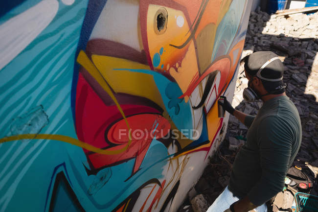 Hochwinkel-Ansicht junger kaukasischer Graffiti-Künstler sprüht Malerei auf verwitterte Wand in der Gasse — Stockfoto