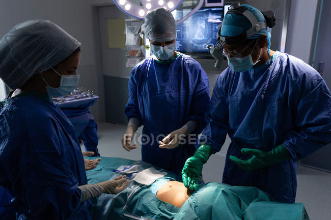 Vista frontal de cirujanos operando en quirófano en el hospital - foto de stock
