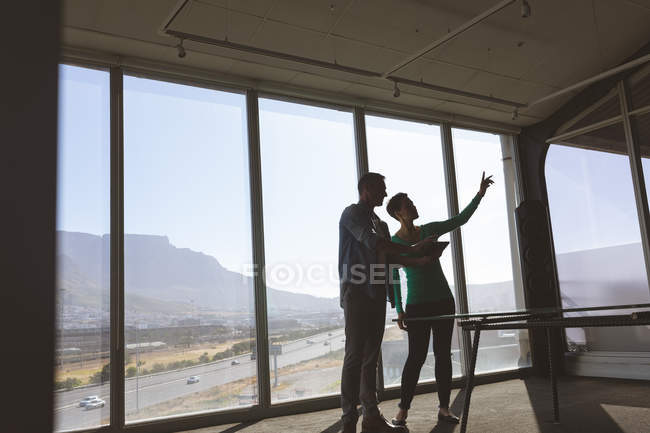 Low angle view of Caucasian architects watching the office while discussing and holding a digital tablet — Stock Photo