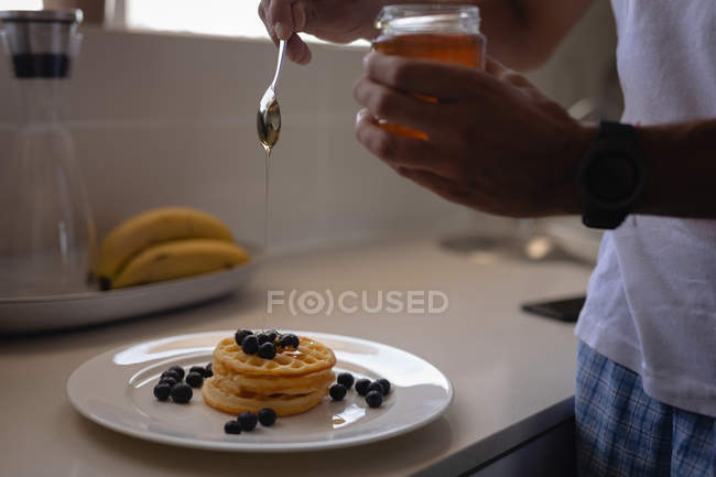 Sección media del hombre preparando el desayuno en la cocina en casa - foto de stock