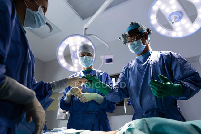 Visão de baixo ângulo dos cirurgiões que realizam a operação no centro cirúrgico do hospital — Fotografia de Stock