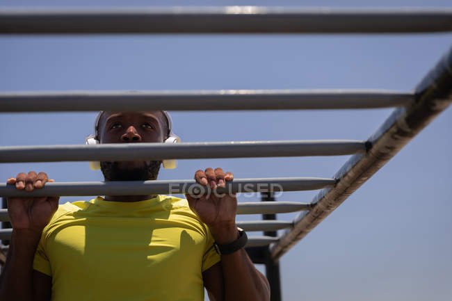 Vista de bajo ángulo del joven afroamericano en forma haciendo ejercicio en el parque en un día soleado - foto de stock