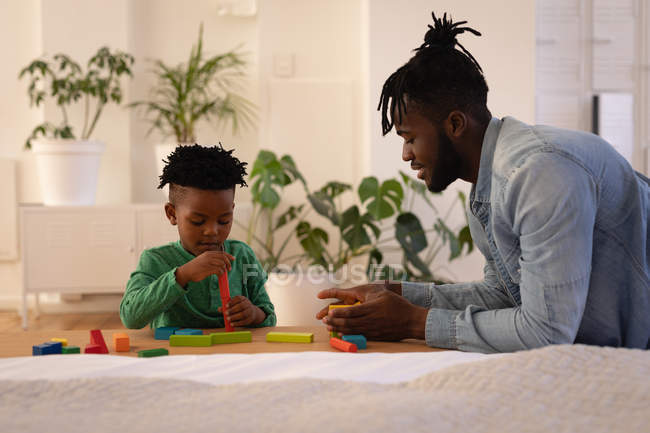 Vista lateral do belo pai afro-americano brincando com o filho em casa — Fotografia de Stock