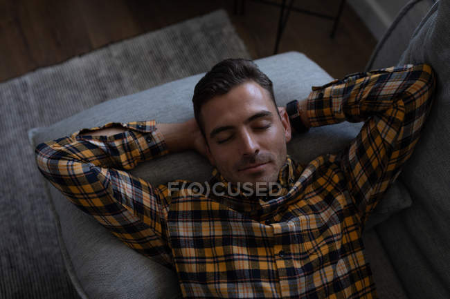 High angle view of young Caucasian man lying on sofa at home — Stock Photo