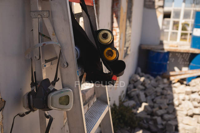 Front view of protective mask and spray paints hanging on ladder — Stock Photo