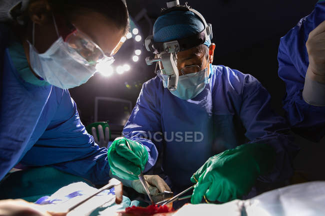 Gros plan sur les chirurgiens concentrés opérant en salle d'opération à l'hôpital — Photo de stock