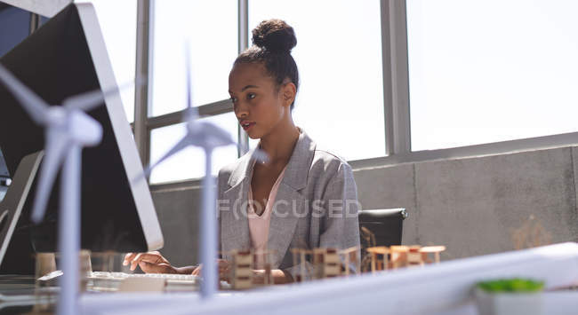 Vista de bajo ángulo de la mujer de negocios de raza mixta que trabaja en la computadora en el escritorio en la oficina - foto de stock