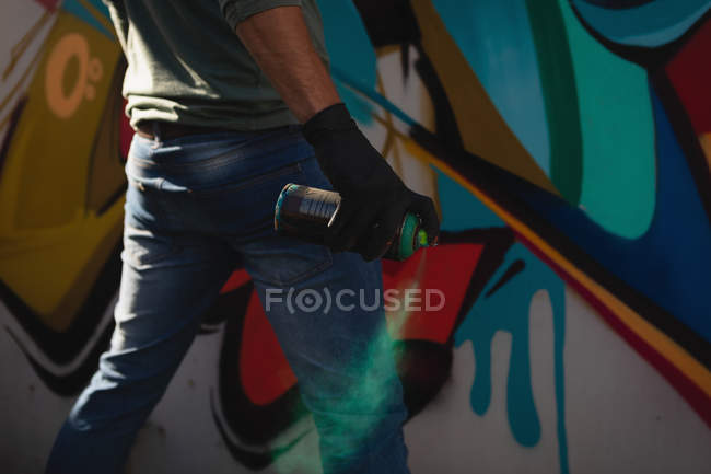 Visão traseira do jovem artista de graffiti caucasiano pintura spray na parede resistida — Fotografia de Stock