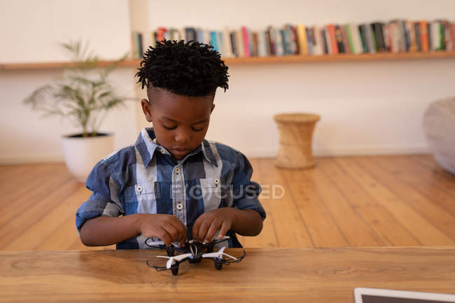 Vista frontal de pequeno menino afro-americano bonito brincando com drone em casa — Fotografia de Stock