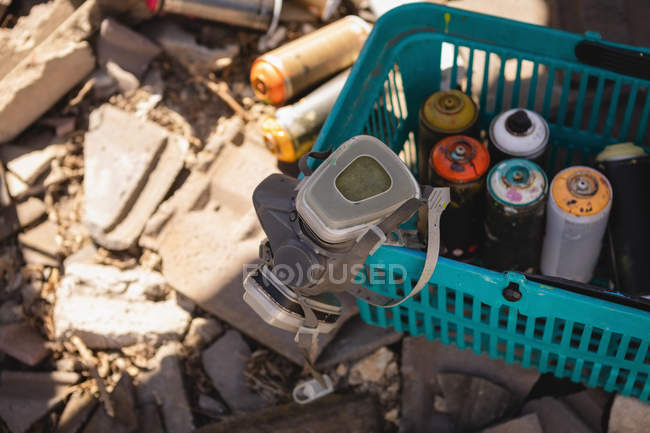 High angle view of protective mask and spray paints inside the basket at alley — Stock Photo