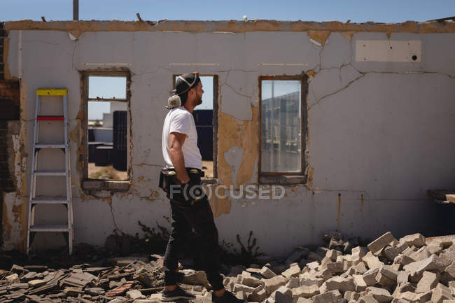 Vista lateral do pensativo jovem artista de graffiti caucasiano andando no beco — Fotografia de Stock