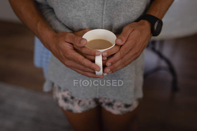 Seção média de casal de pé com o braço ao redor enquanto toma uma xícara de café — Fotografia de Stock