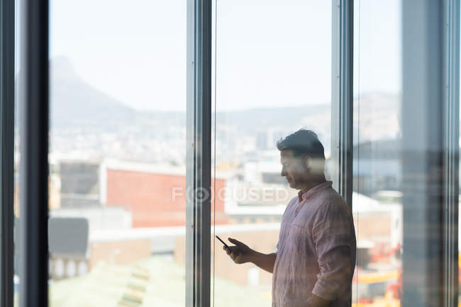 Seitenansicht eines reifen kaukasischen Geschäftsmannes mit Handy im Büro — Stockfoto