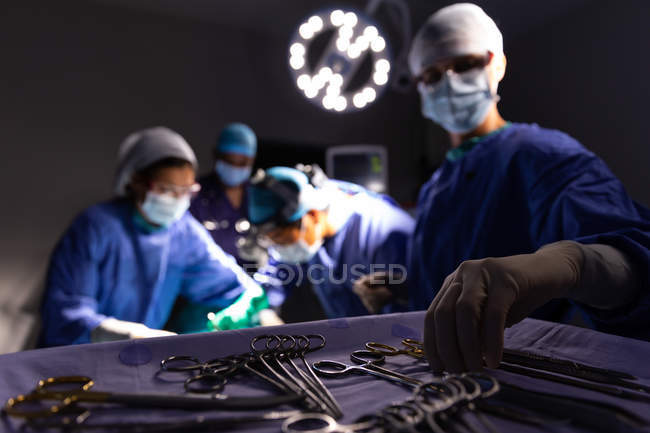 Vista lateral de cirujanos concentrados realizando operación en quirófano en el hospital - foto de stock