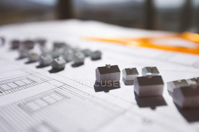 Close up of little house models over blueprint on desk in office — Stock Photo