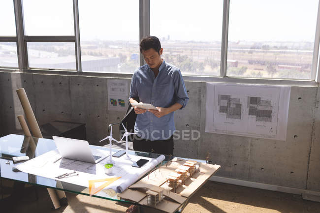 Vista de ángulo alto del joven ejecutivo asiático usando tableta digital en la oficina de arquitectura - foto de stock