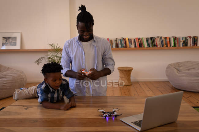 Frontansicht glücklicher afrikanisch-amerikanischer Vater und Sohn beim Spielen mit Drohne auf dem heimischen Tisch — Stockfoto