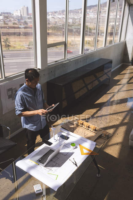Visão de alto ângulo do jovem executivo masculino asiático usando tablet digital no escritório de arquitetura — Fotografia de Stock