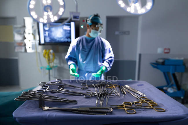 Vista frontal del equipo quirúrgico en una mesa en la sala de operaciones en el hospital con el cirujano en el fondo - foto de stock