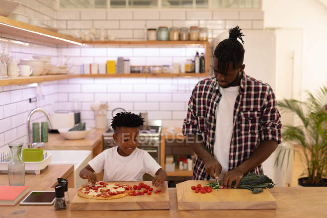 Schriftbild des gutaussehenden afrikanisch-amerikanischen Vaters und Sohnes beim gemeinsamen Kochen in der heimischen Küche — Stockfoto