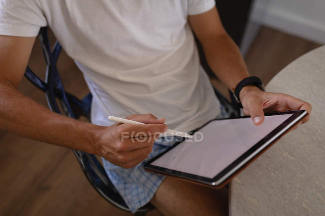 Seção intermediária do designer gráfico usando tablet gráfico na cozinha em casa — Fotografia de Stock