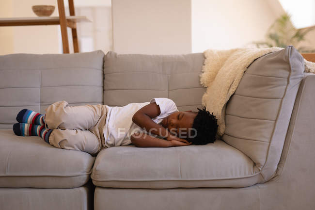 Фронтальний вид милий афро-американських хлопчик спить на дивані в домашніх умовах — стокове фото
