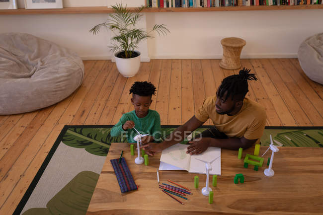 High angle view of African-American father teaching about wind turbine to his son at home — Stock Photo
