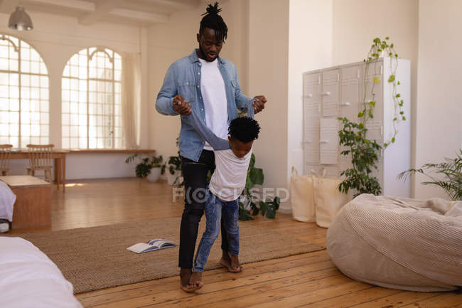 Vista frontal del padre y el hijo afroamericanos jugando en casa - foto de stock