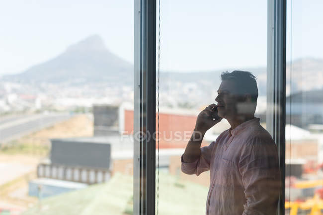 Vista laterale di maturo uomo d'affari caucasico che parla sul cellulare in ufficio — Foto stock