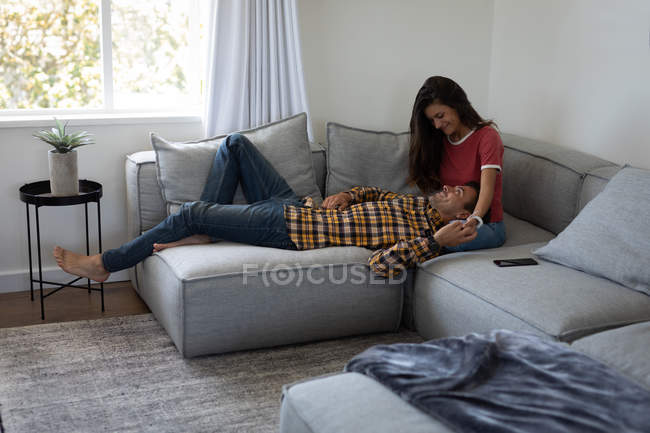 Front view of beautiful multi-ethnic couple interacting with each other on sofa at home — Stock Photo