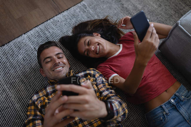 Blick aus der Vogelperspektive auf ein glückliches junges multiethnisches Paar, das zu Hause ein Selfie mit dem Handy macht. sie lächeln — Stockfoto