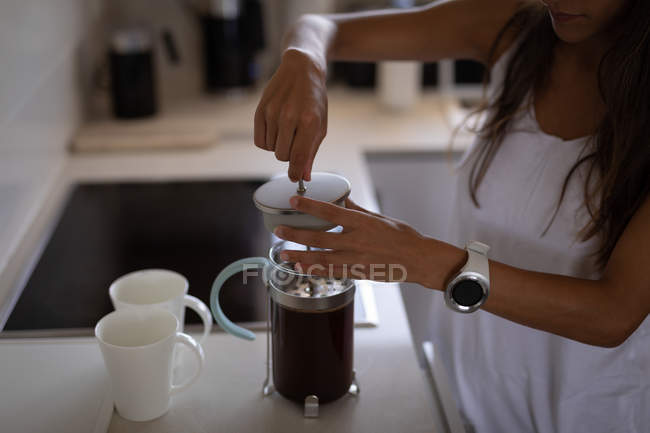 Mittelteil der Frau, die Kaffee in Kaffeemaschine kocht, steht in der Küche — Stockfoto