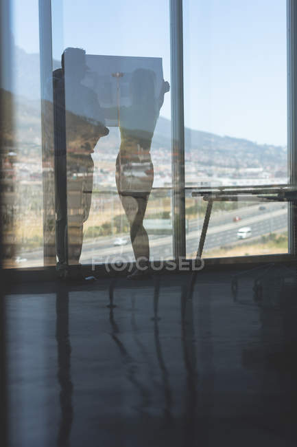 Vista posteriore di maturo maschio caucasico e bionda caucasica architetti femminili discutendo sopra cianografia in ufficio — Foto stock