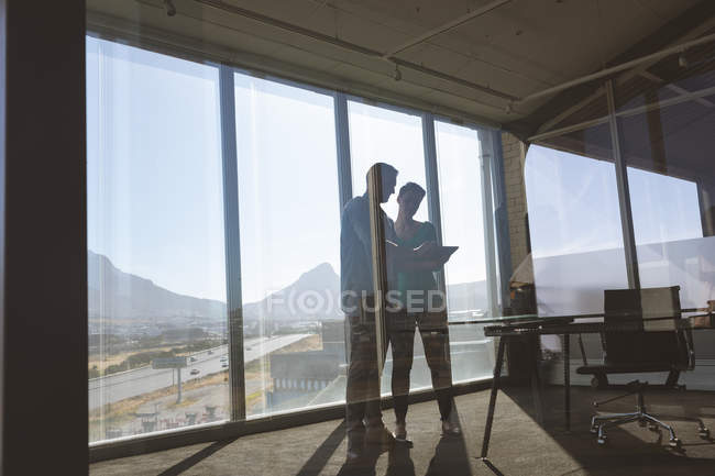 Vista de baixo ângulo de arquitetos caucasianos discutindo sobre um tablet digital no escritório — Fotografia de Stock