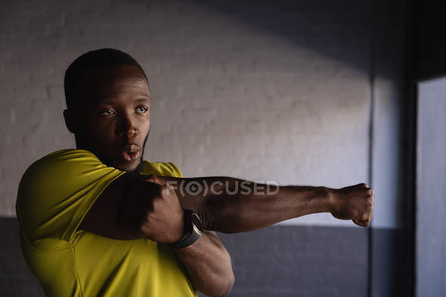 Front view of young African-American fit man doing hand stretch exercise under the bridge — Stock Photo