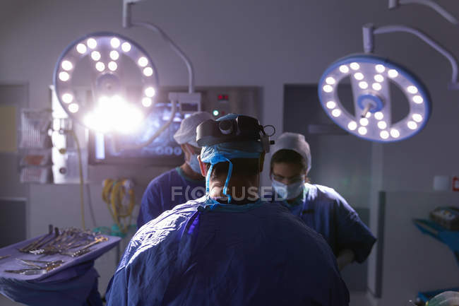 Vue arrière des chirurgiens opérant en salle d'opération à l'hôpital — Photo de stock