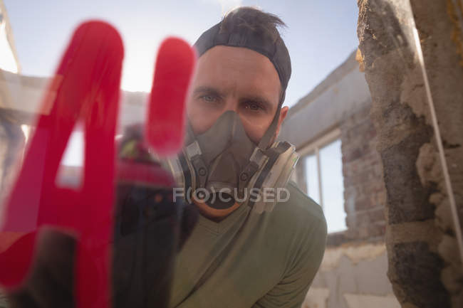 Front view of young Caucasian graffiti artist spray painting on glass at street side — Stock Photo