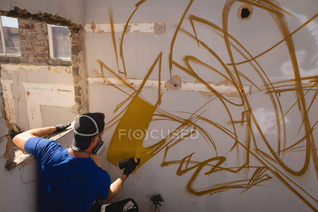 Visão traseira do jovem artista de grafite caucasiano pintura em spray parede resistida — Fotografia de Stock