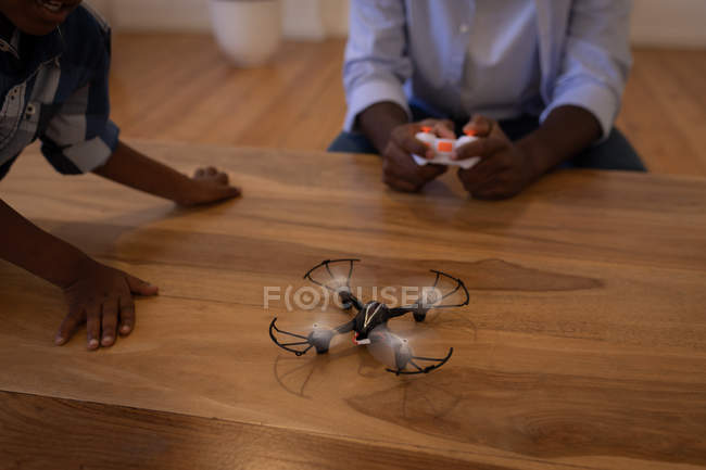Vater und Sohn spielen zu Hause mit Drohne auf Tisch — Stockfoto