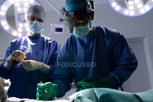 Visão de baixo ângulo dos cirurgiões que realizam a operação no centro cirúrgico do hospital — Fotografia de Stock